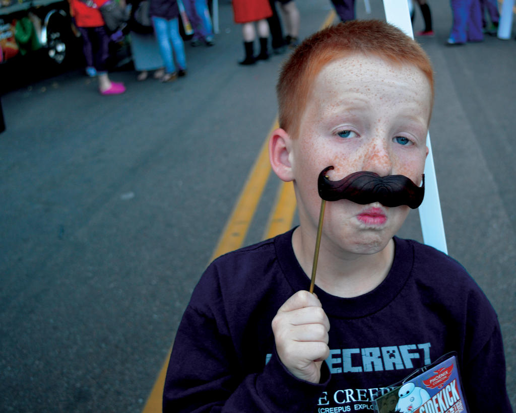Photograph of a child holding a mustache prop