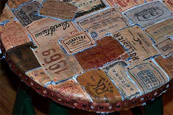 Round tabletop mosaicked from reclaimed denim labels, with a copper-riveted leather rim