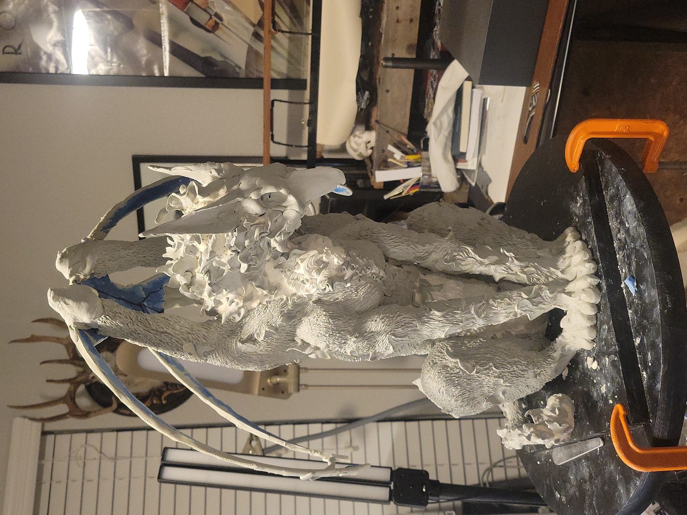 Wolf-dragon hybrid sculpted in clay, wings on armature, work in progress in the studio